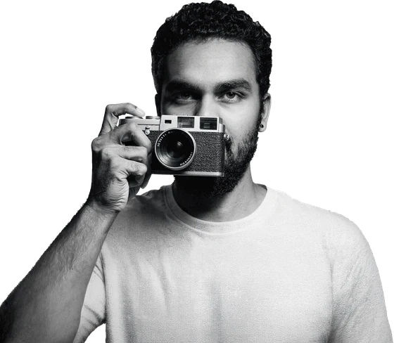 Rudraksha Chawla holding a rangefinder camera, cut out in black and white